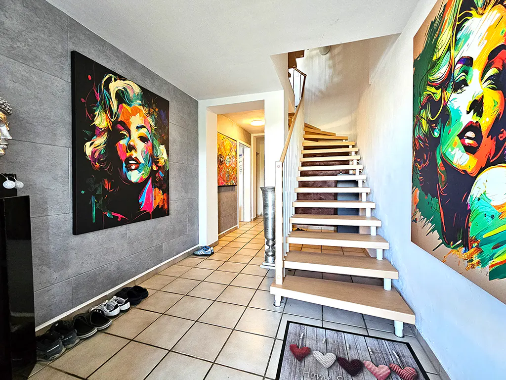 Hallway with tile floor, stairs, and colorful Marilyn Monroe art on the walls.