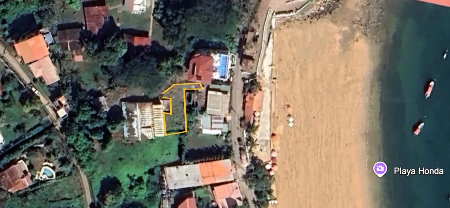 Aerial view of a property outlined in yellow, near Playa Honda, with houses, trees, and a sandy beach.