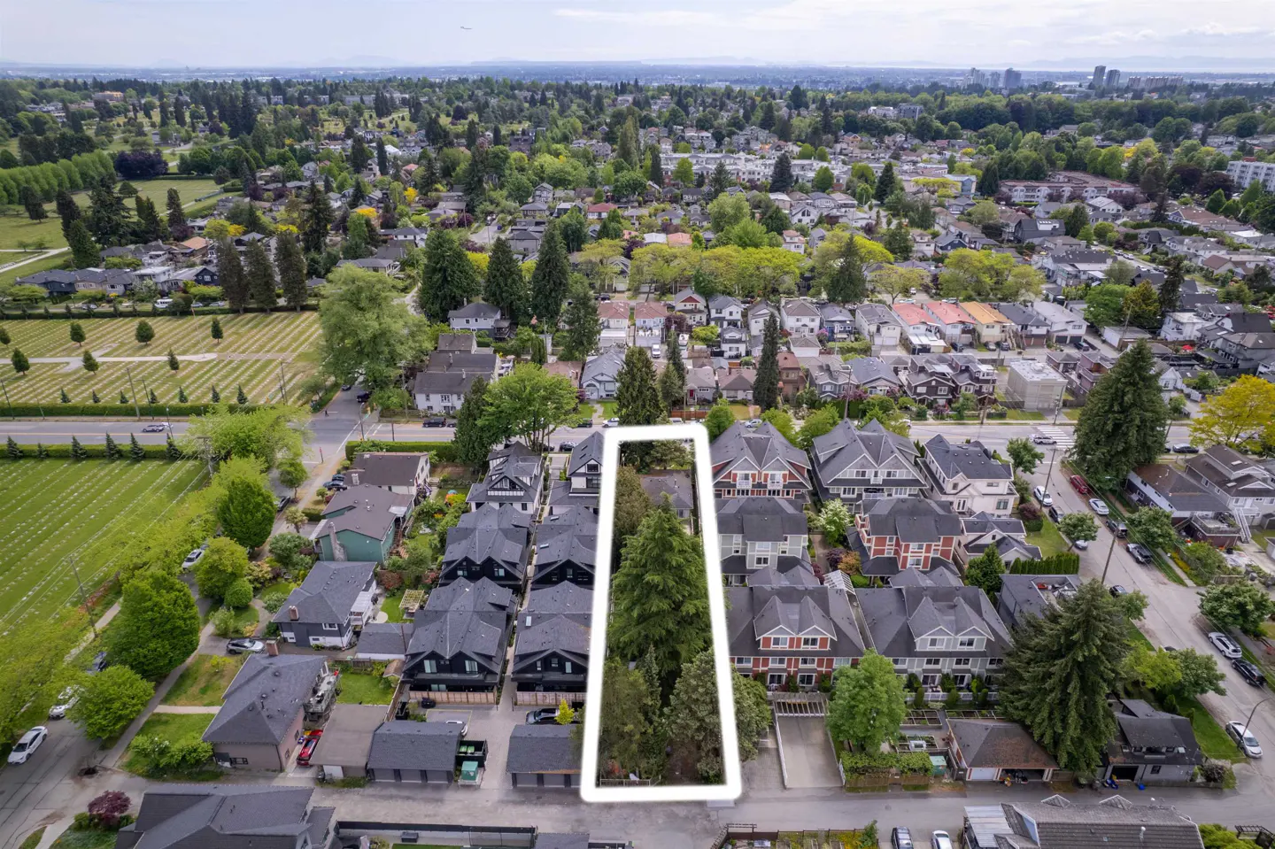 Aerial view of a property outlined in white, surrounded by houses and trees in a residential neighborhood.