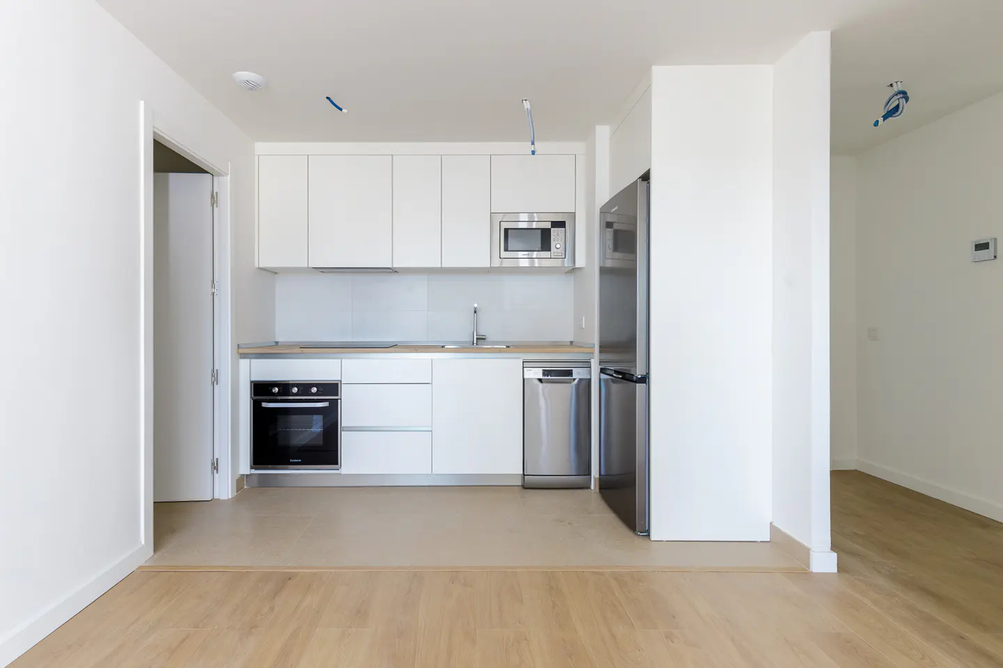 Bright, modern kitchen with white cabinets, stainless steel appliances, and light wood floors.