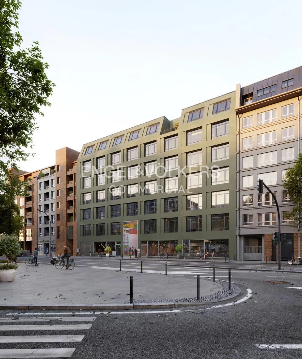 Exterior view of a modern, multi-story green building with many windows, Engel & Volkers logo, and a plaza with people on bikes.