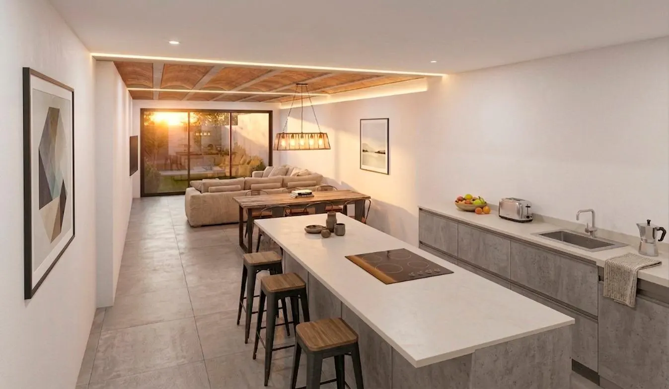 A modern open-concept kitchen and living room with white walls, a large island with stools, and a view of the backyard at sunset.
