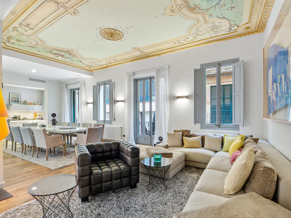 Bright living room with a painted ceiling, a large sectional sofa, and a dining table with chairs.