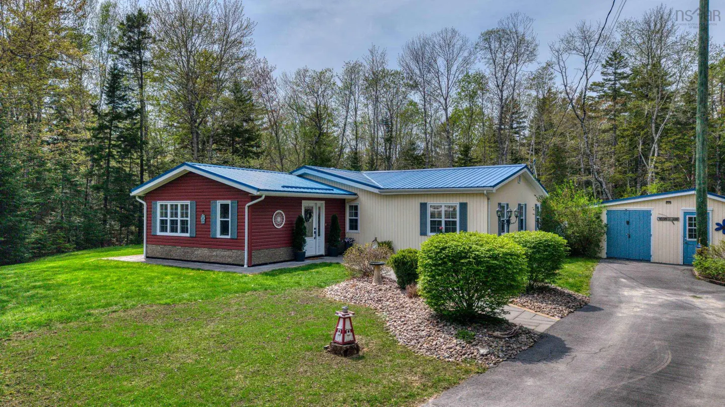 A single-story home with a blue roof, red and beige siding, green shutters, and a matching shed.