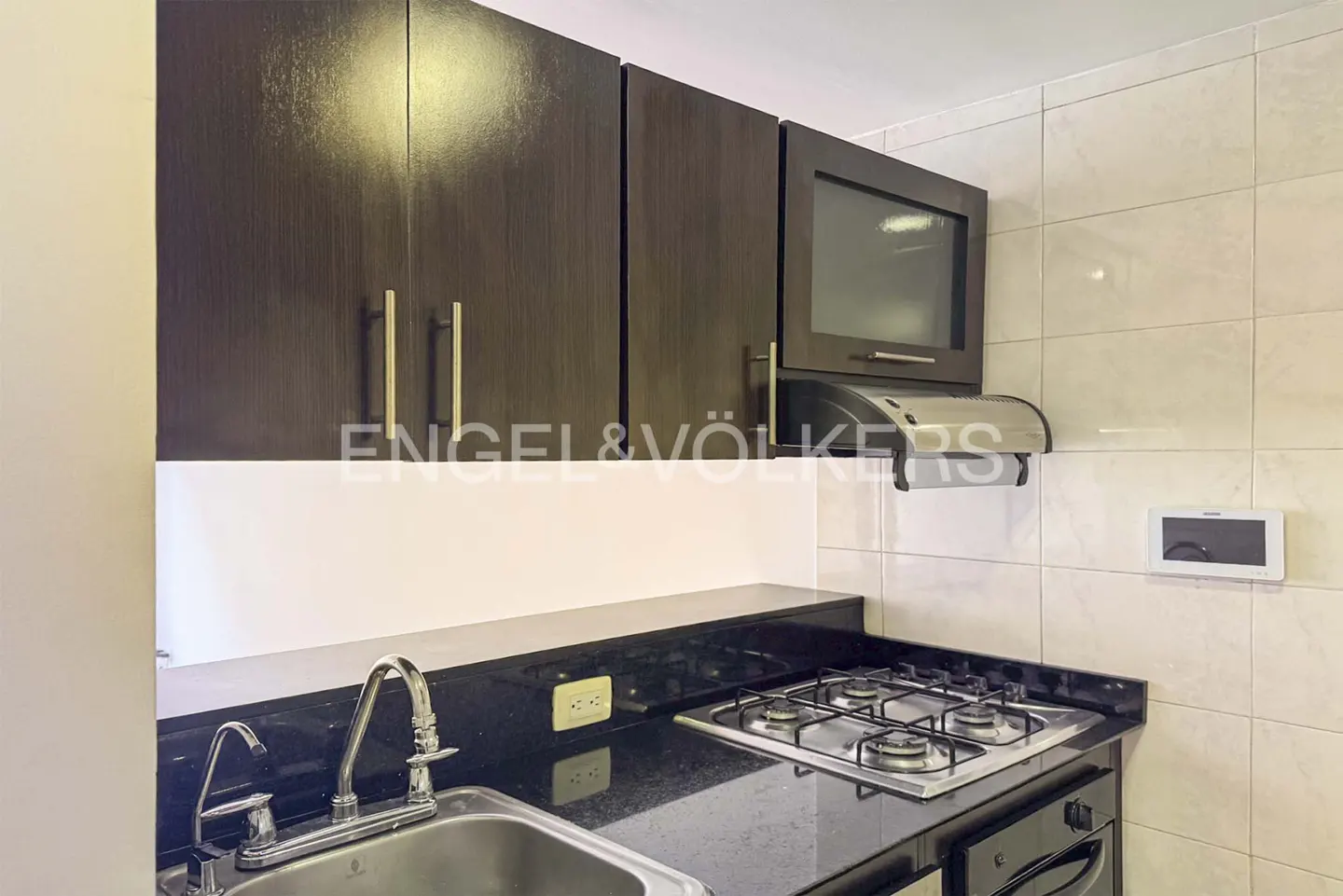 Modern kitchen with dark wood cabinets, black granite countertops, stainless steel sink, and a gas stovetop.