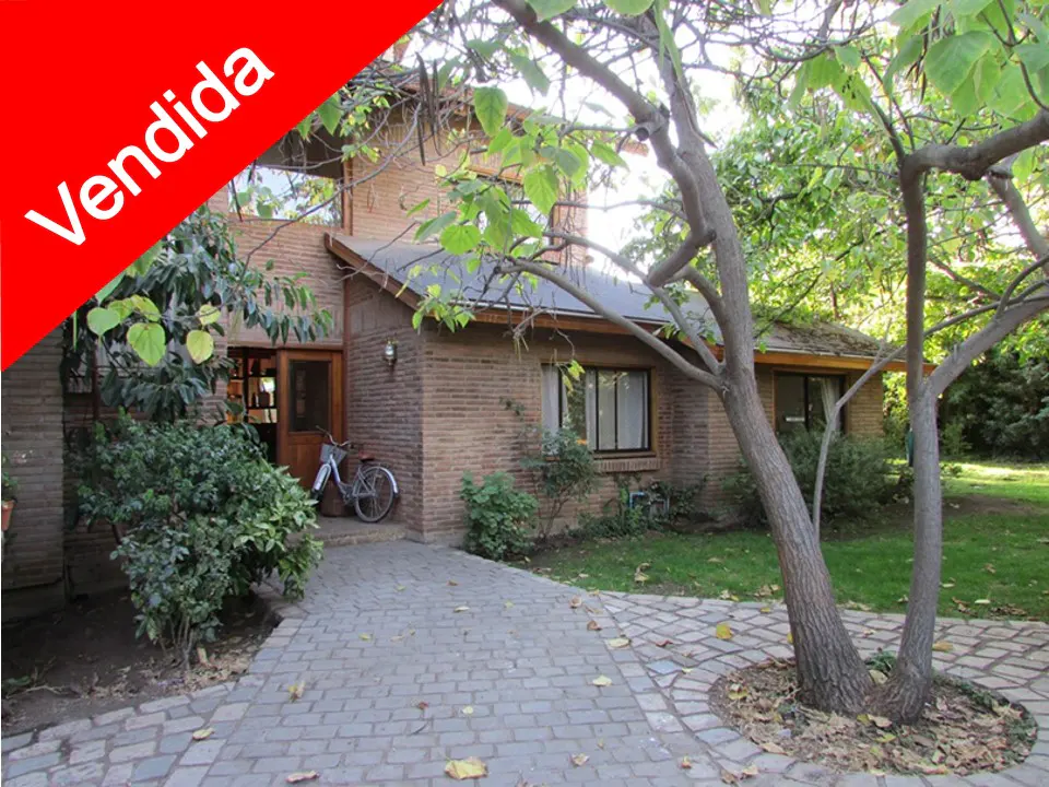 Brick house with a "Vendida" (sold) banner, a stone path, and a bicycle parked near the wooden front door.