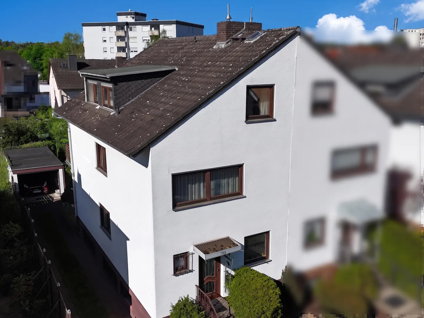 Two-story white house with a brown roof, brown window frames, and a small front yard with greenery.