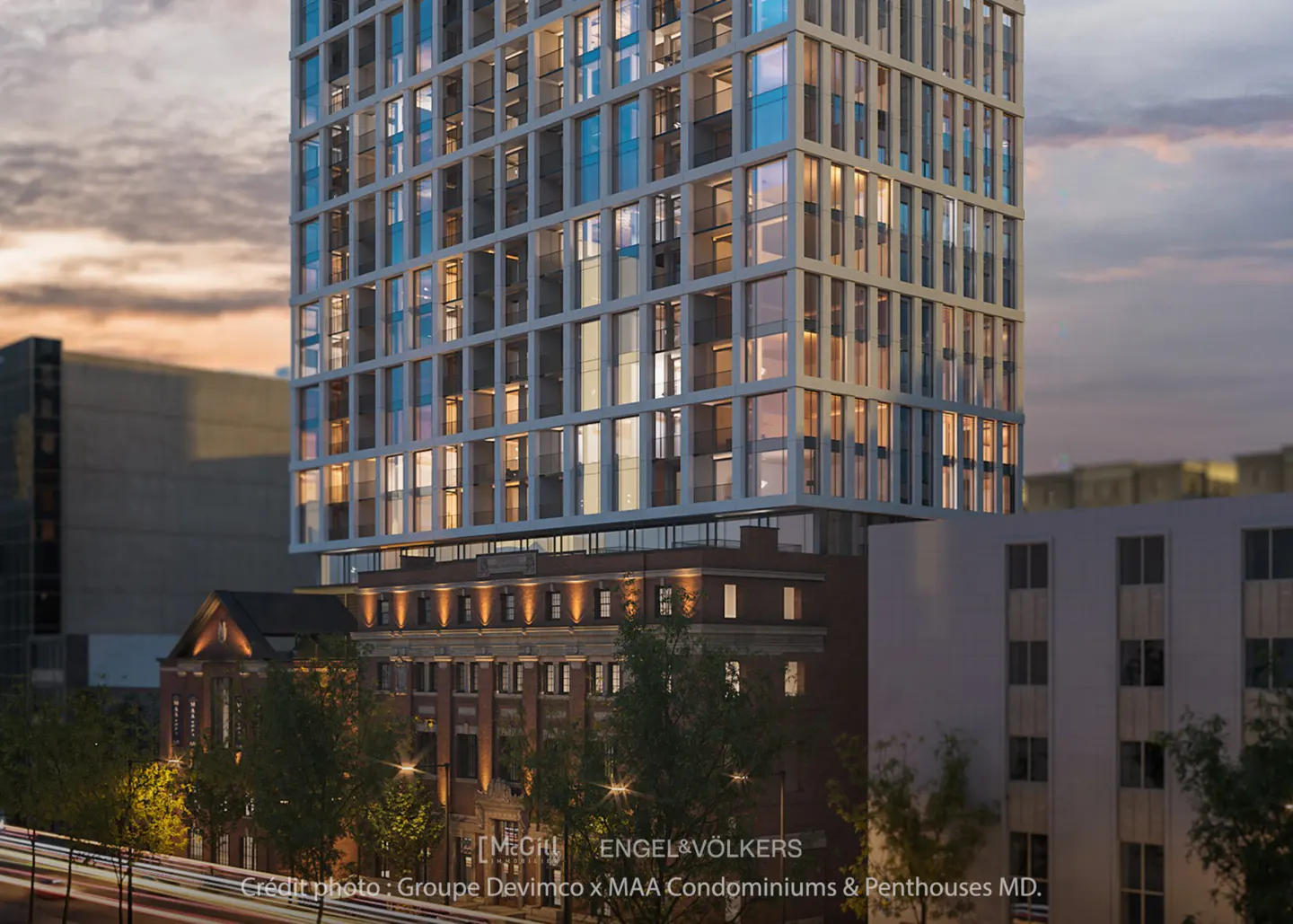 Modern high-rise condo building with a grid-like facade, atop a brick building at dusk.