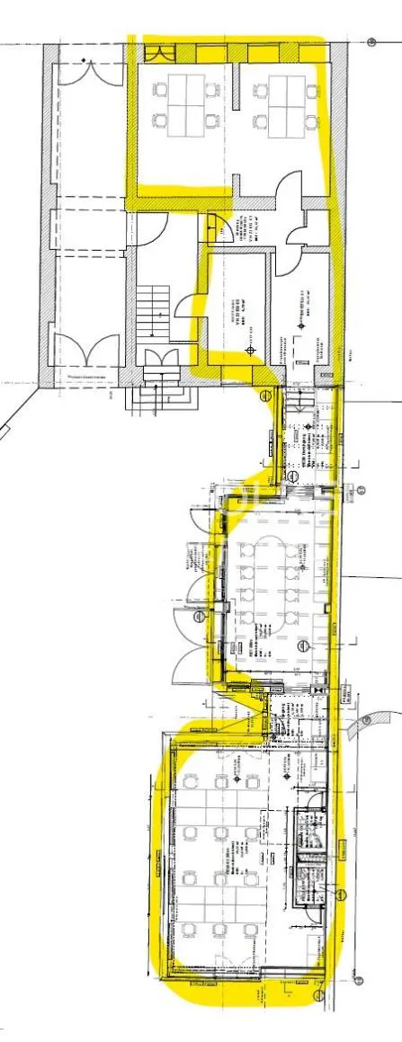 Floor plan with yellow highlights showing the layout of a building with offices, stairs, and rooms.
