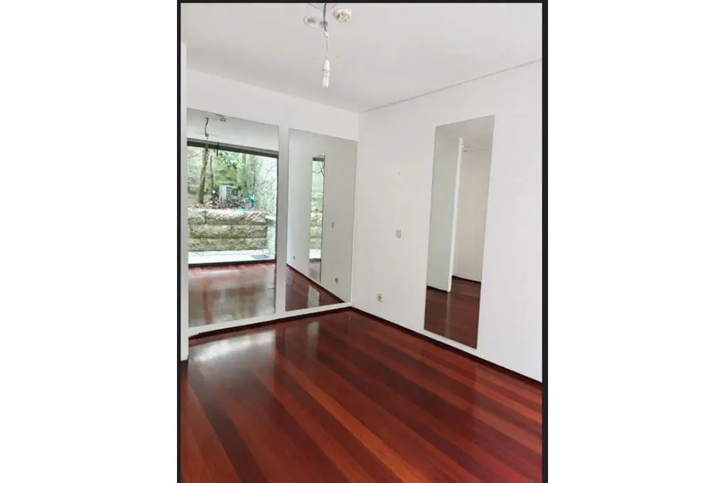 A bright room with cherry wood floors, white walls, and three mirrors reflecting the outside.