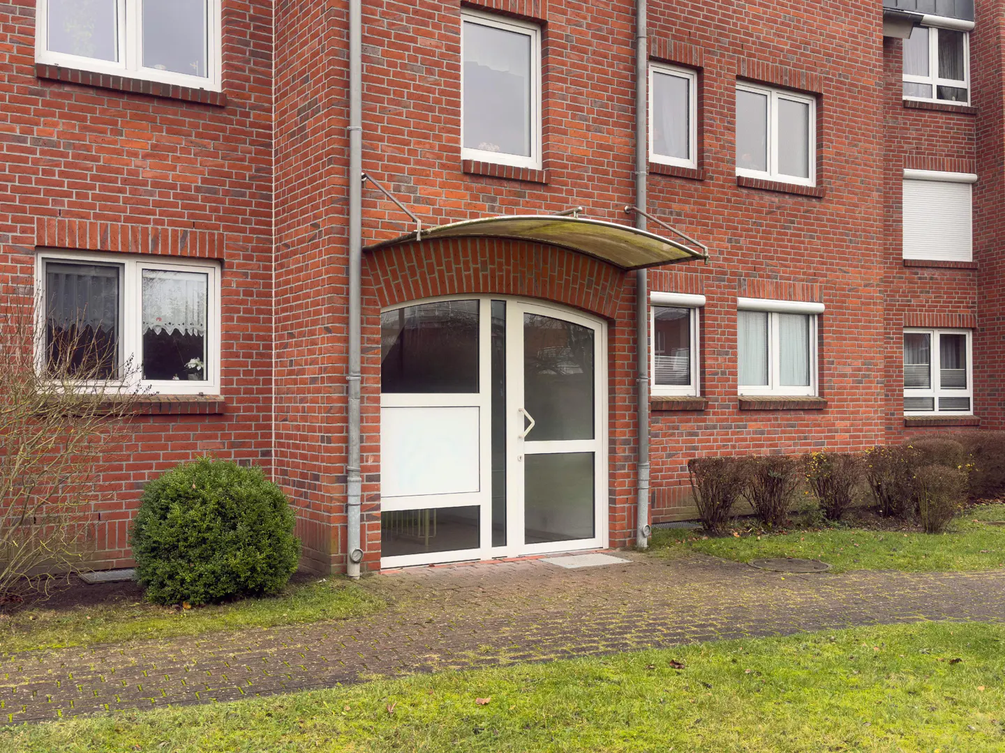 Exterior of a red brick apartment building with a white door and awning.