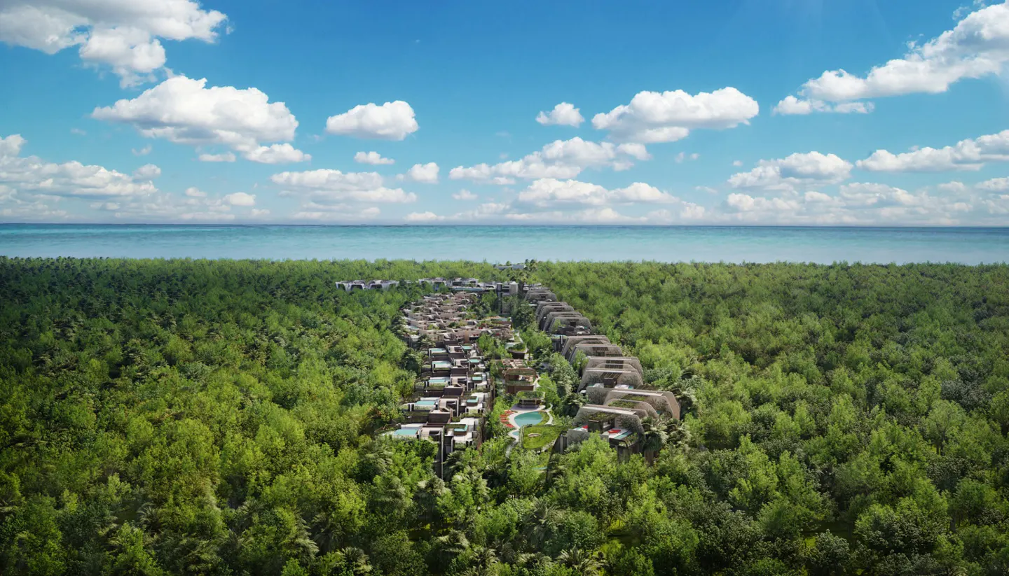 Aerial view of a resort nestled in a lush green forest, with the ocean and blue sky in the background.