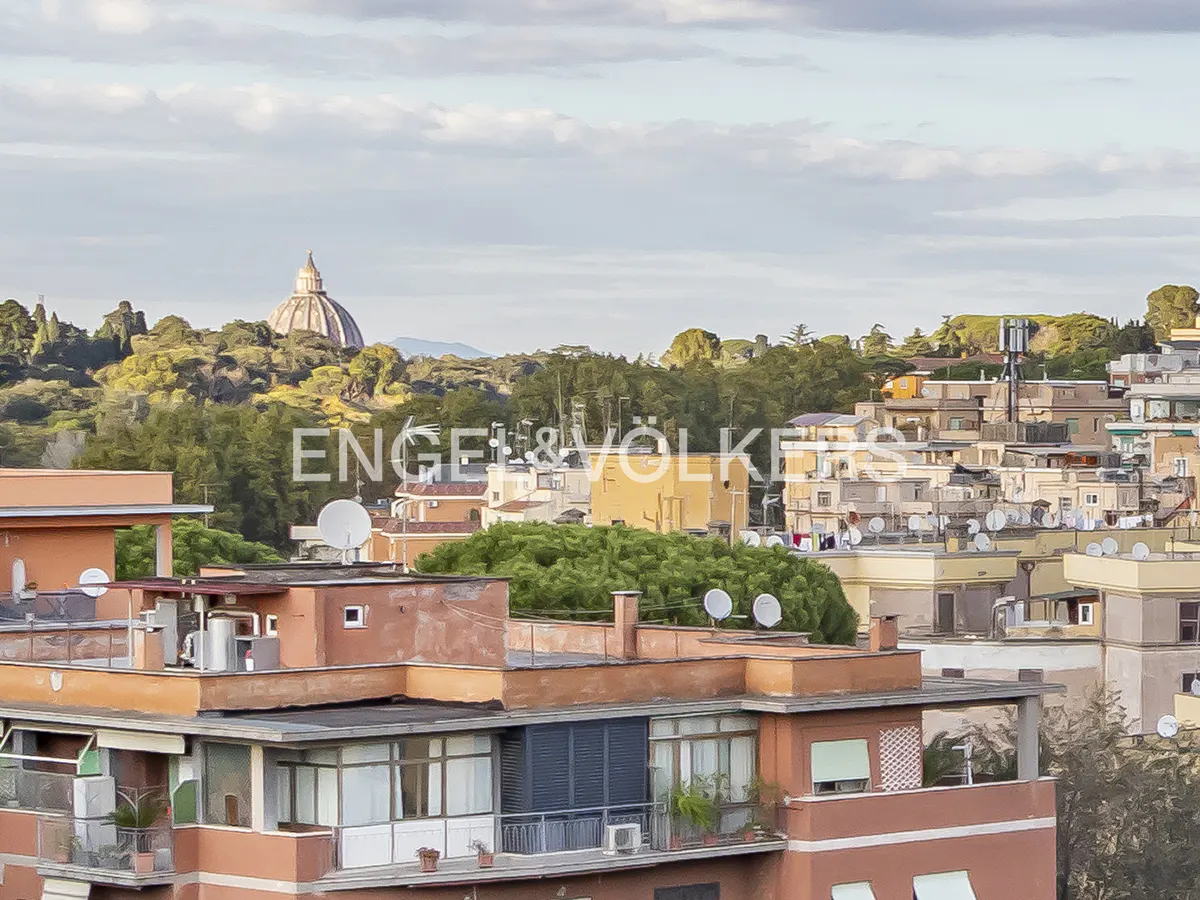 Rooftop view of Rome, Italy, with terracotta buildings, satellite dishes, and St. Peter's Basilica dome in the distance. Trees and cloudy sky.