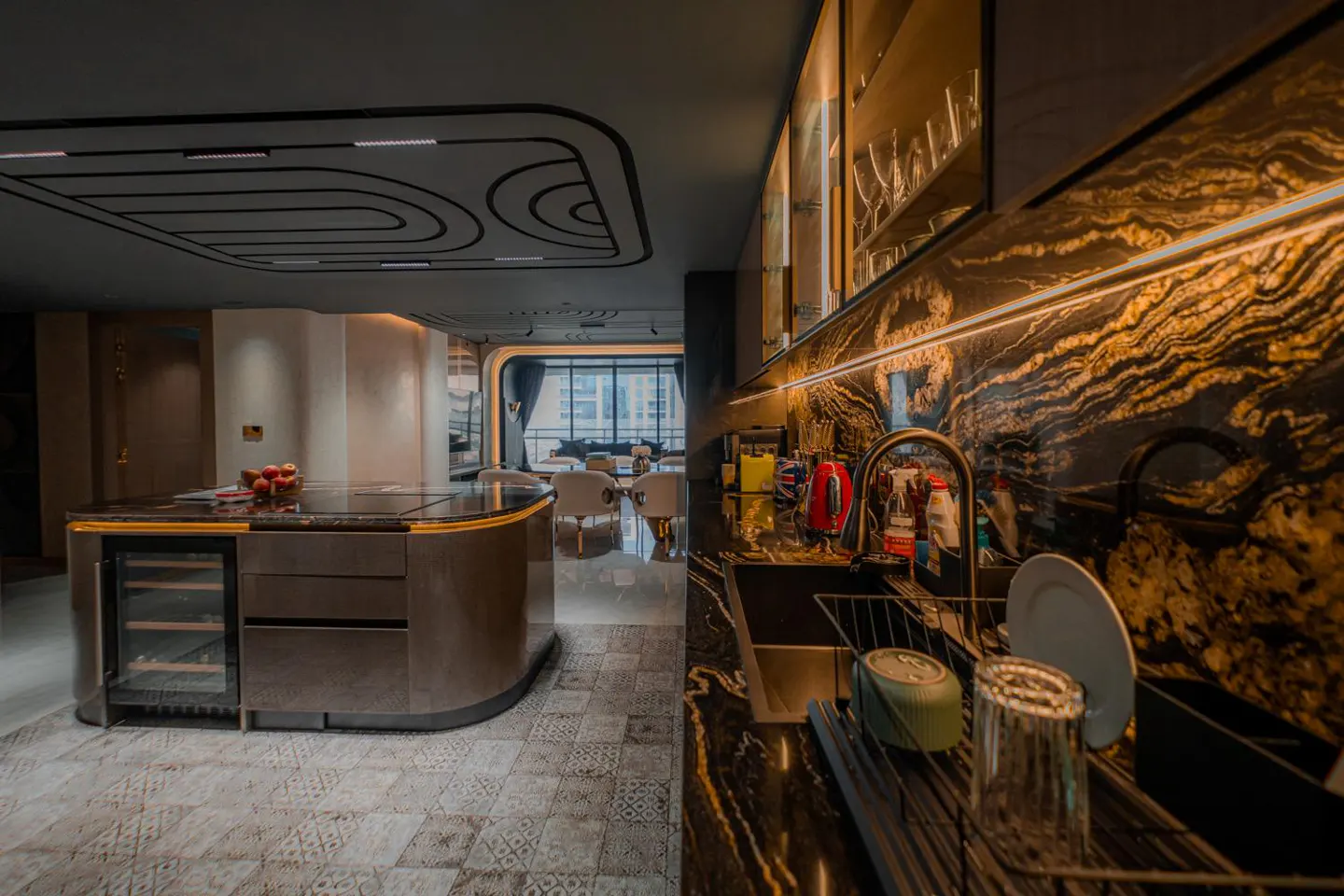 A modern kitchen with black and gold marble countertops, a brown island with a wine cooler, and a view of a dining area.