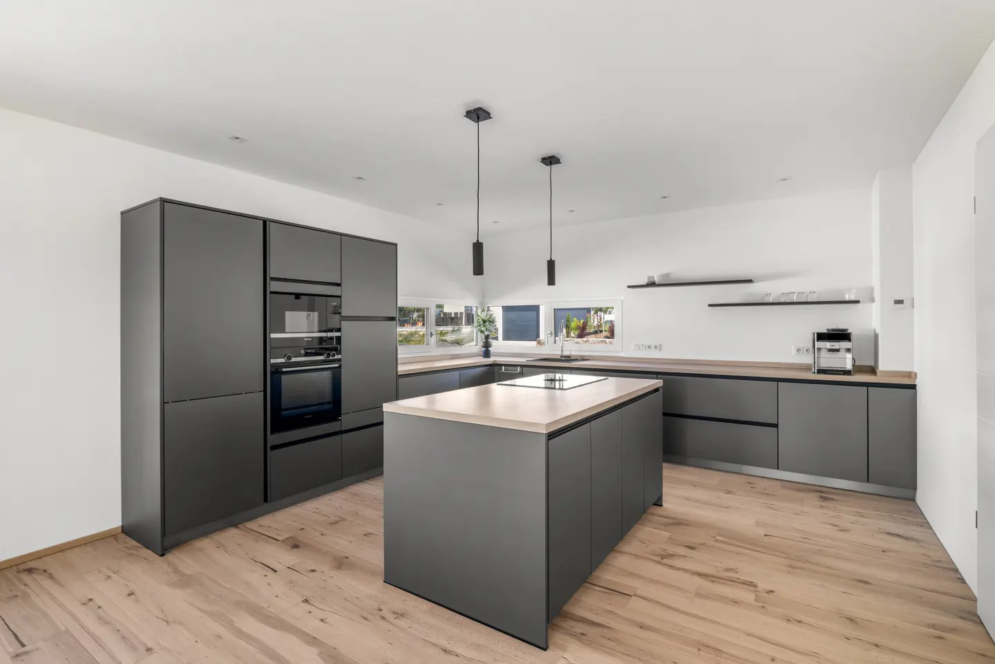 Modern kitchen with matte grey cabinets, a central island with a light wood countertop, and light hardwood flooring.