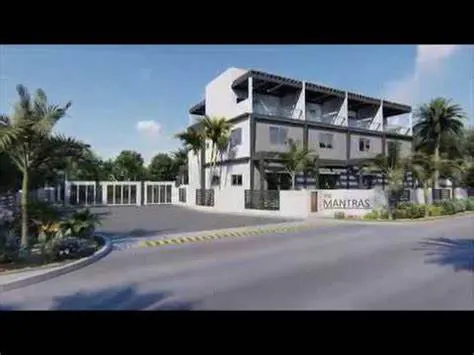 Exterior view of "The Mantras" townhouses, a modern three-story building with palm trees and a gated entrance.