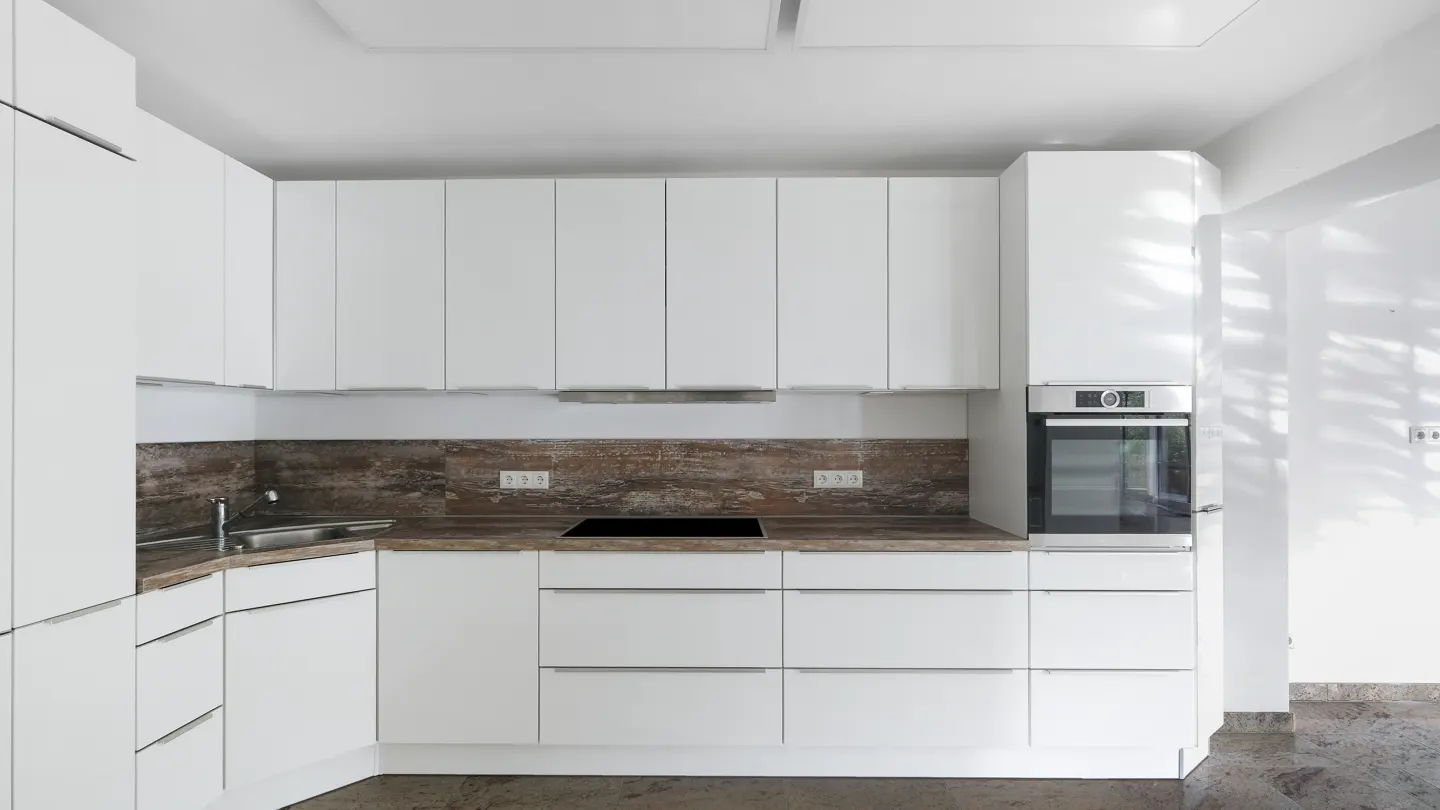 Modern kitchen with white cabinets, wood-look countertops, a built-in oven, and a stainless steel sink.