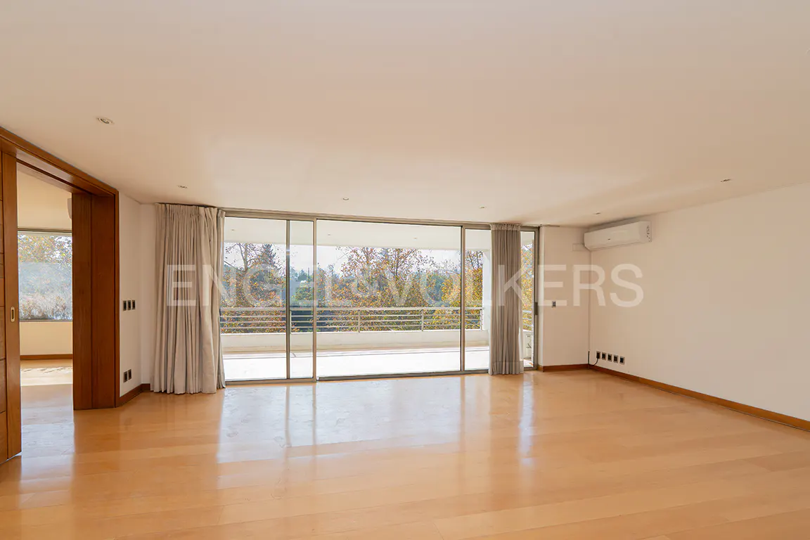 Bright, empty room with wood floors, white walls, and large sliding glass doors to a balcony with trees in the background.