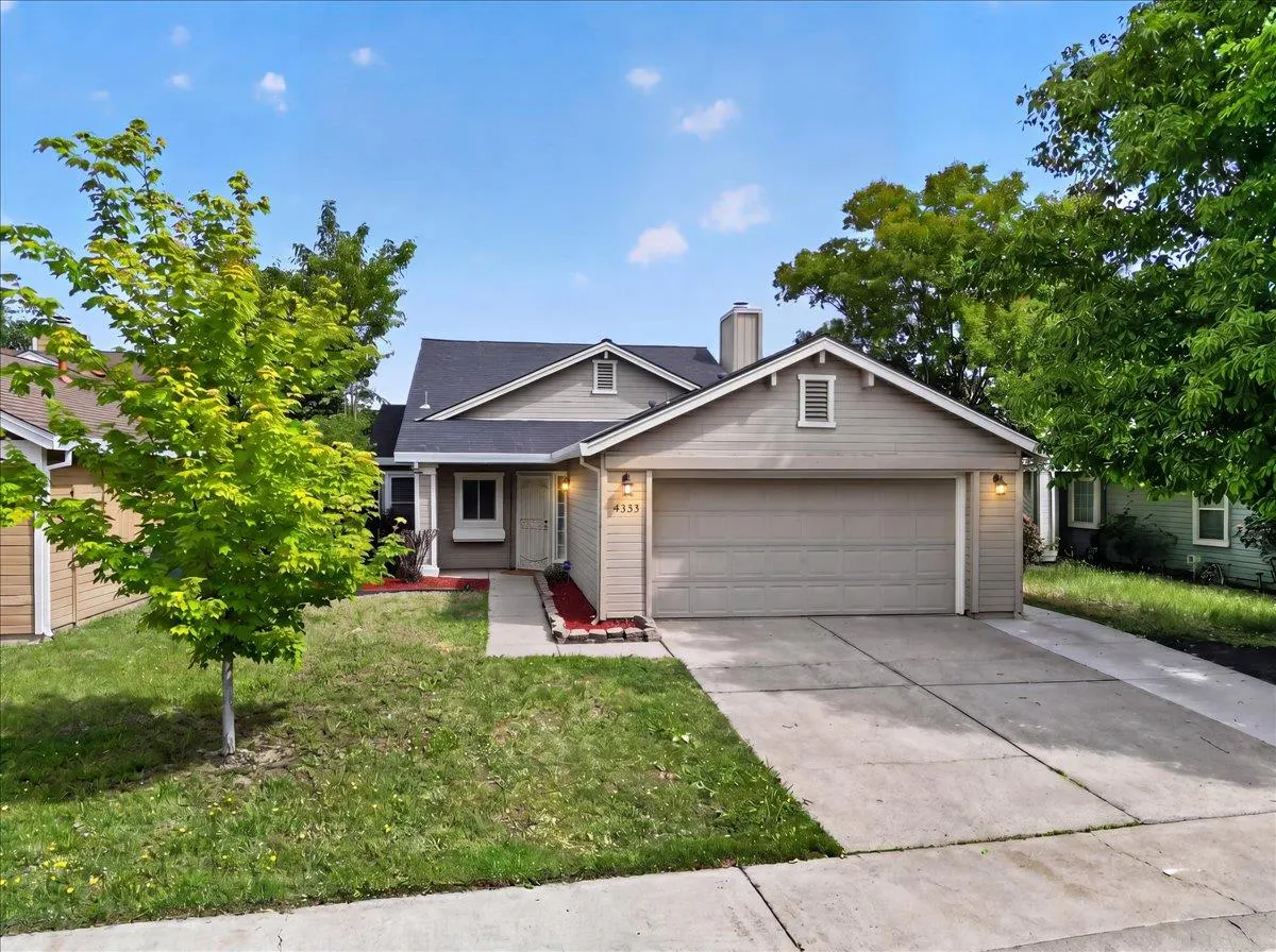 Beige single-story house with a gray roof, a two-car garage, and a green lawn under a blue sky.