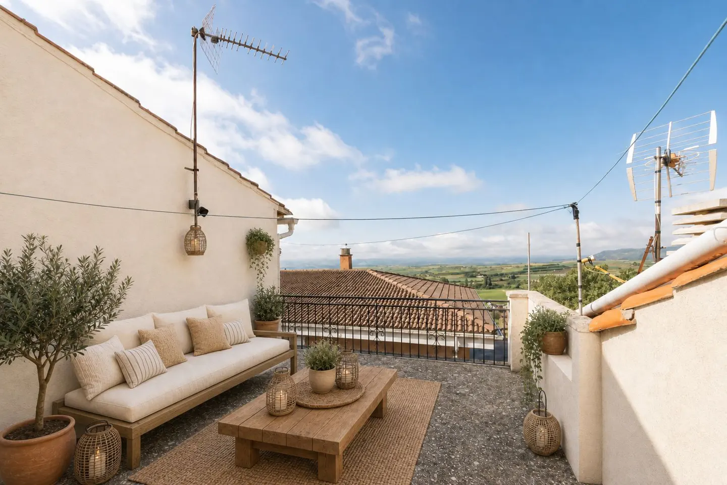 Outdoor patio with a white couch, wooden table, and potted plants. A view of rolling hills is visible in the background.