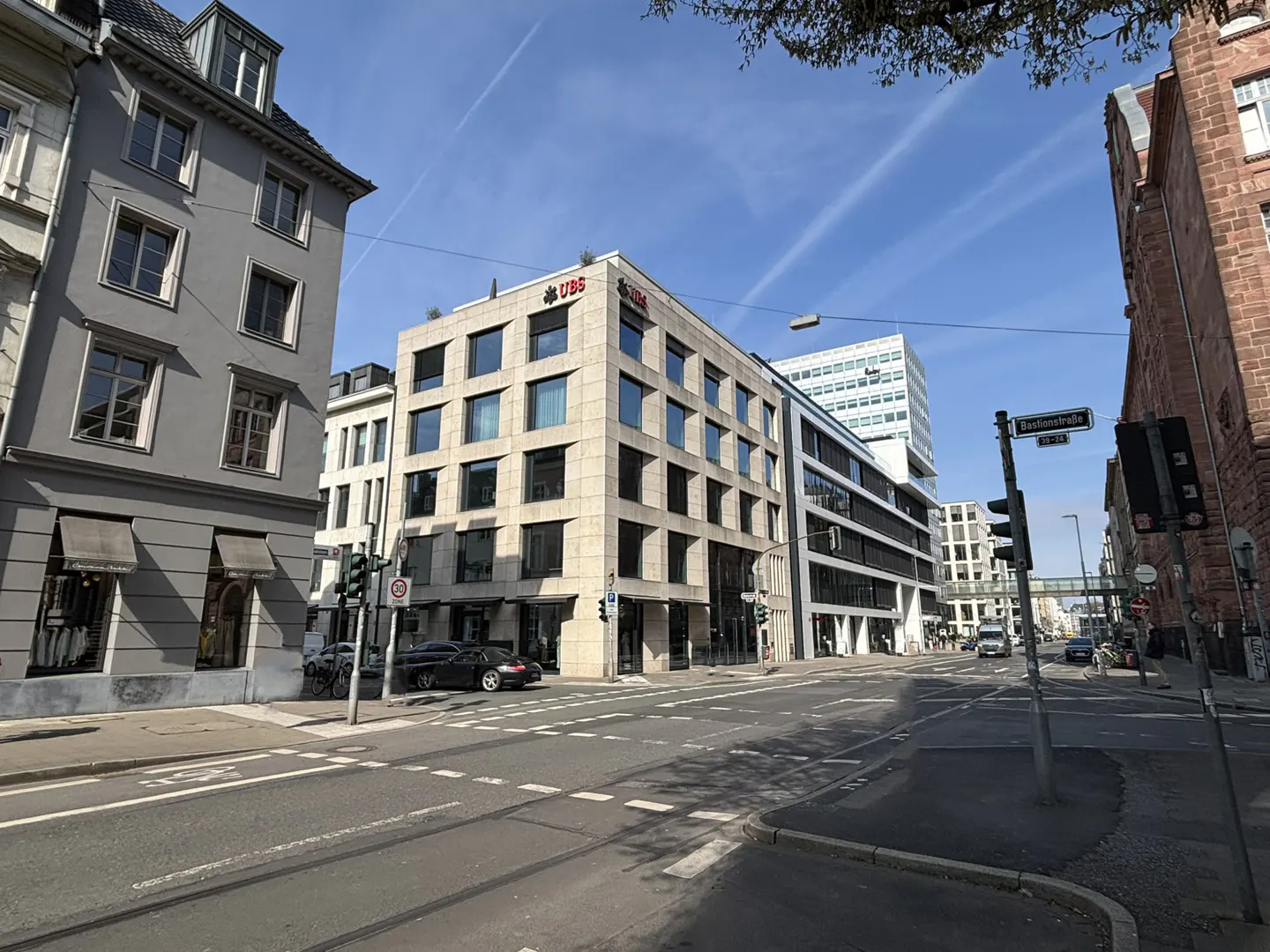 Street view of the UBS building in Dusseldorf, Germany, with cars on the road and blue sky above.