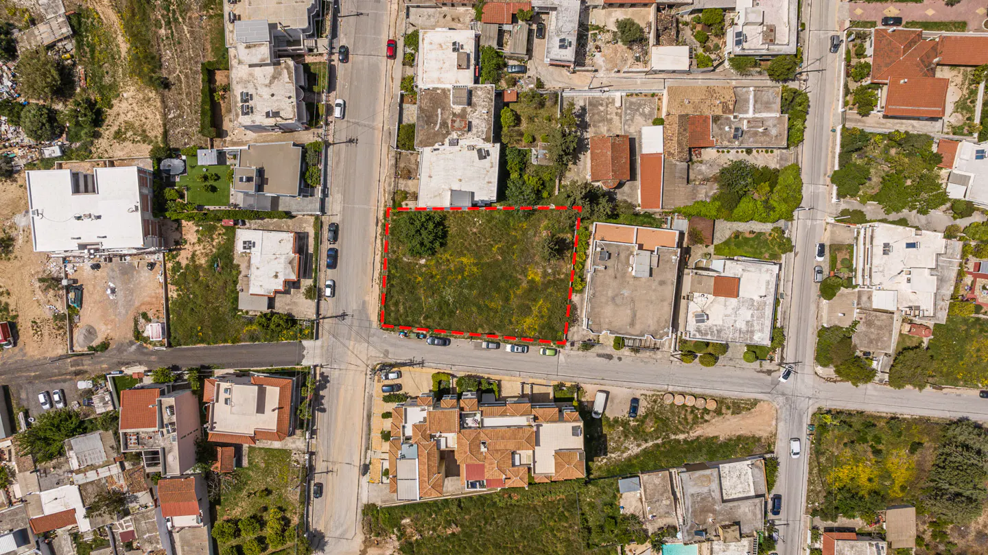 Aerial view of a vacant lot outlined in red, surrounded by streets and buildings in a residential area.