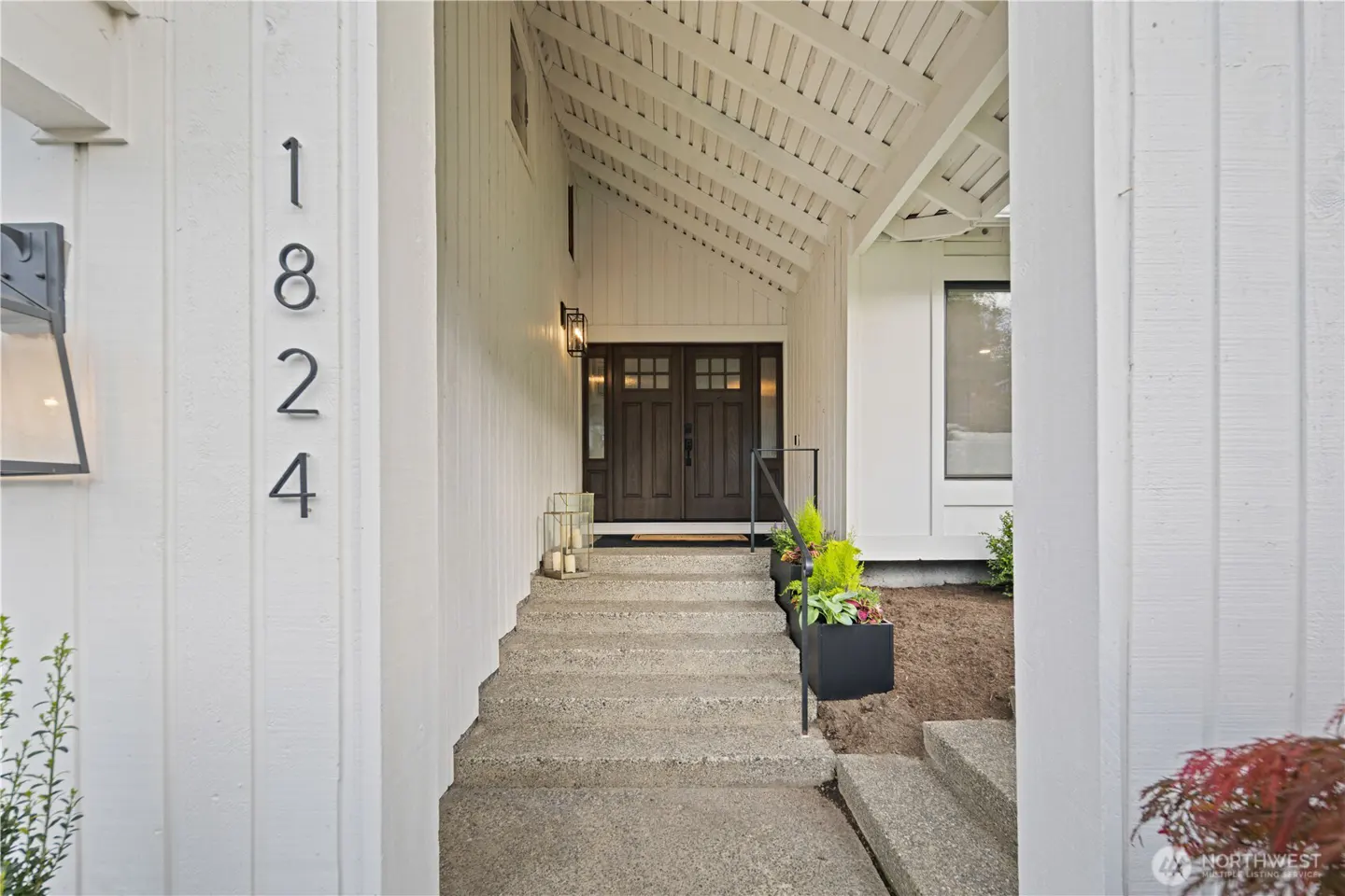 Exterior of a white house with the address 1824, stone steps, and a dark wood double door.