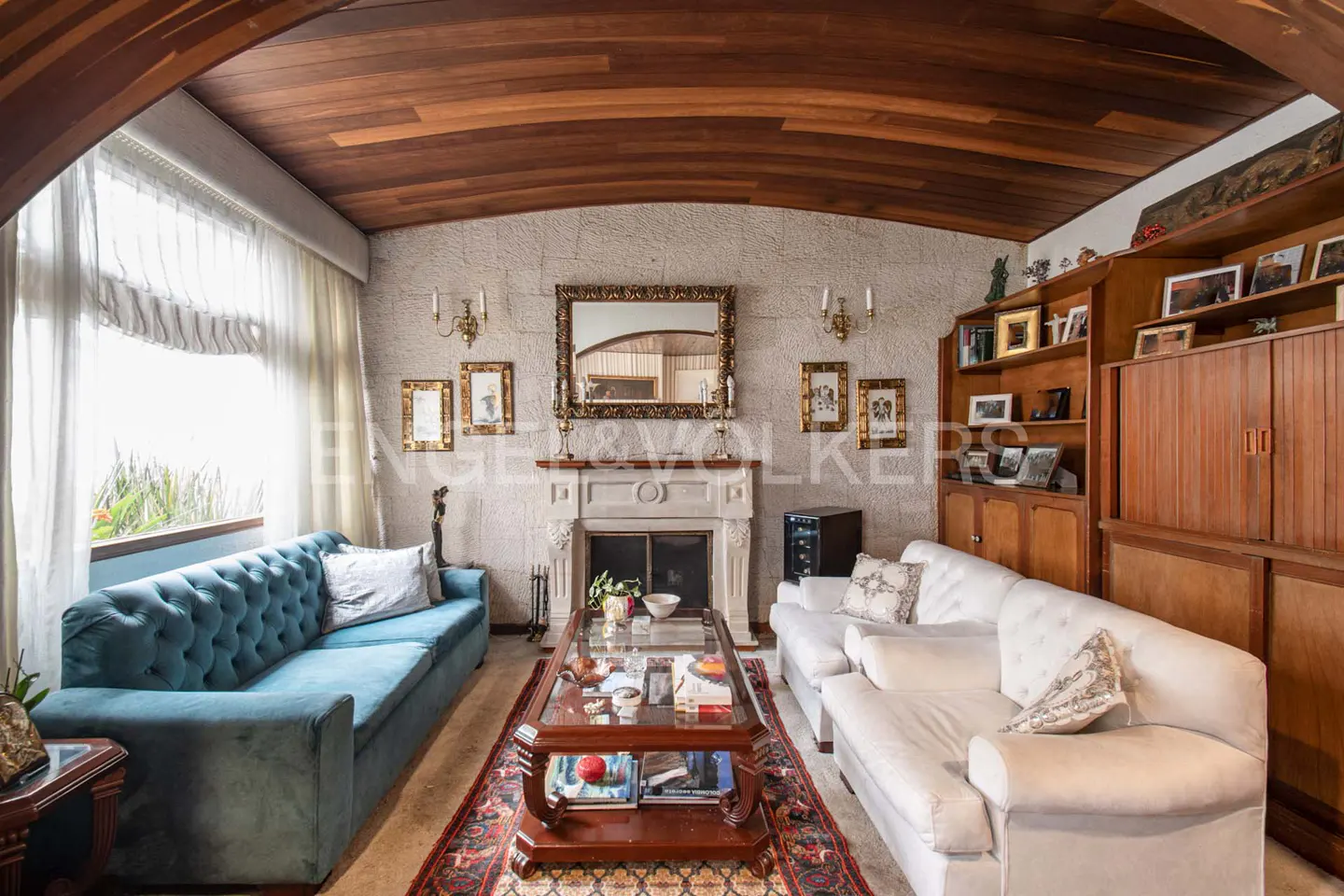Living room with a blue tufted sofa, a white sofa, a fireplace, and a wood ceiling.