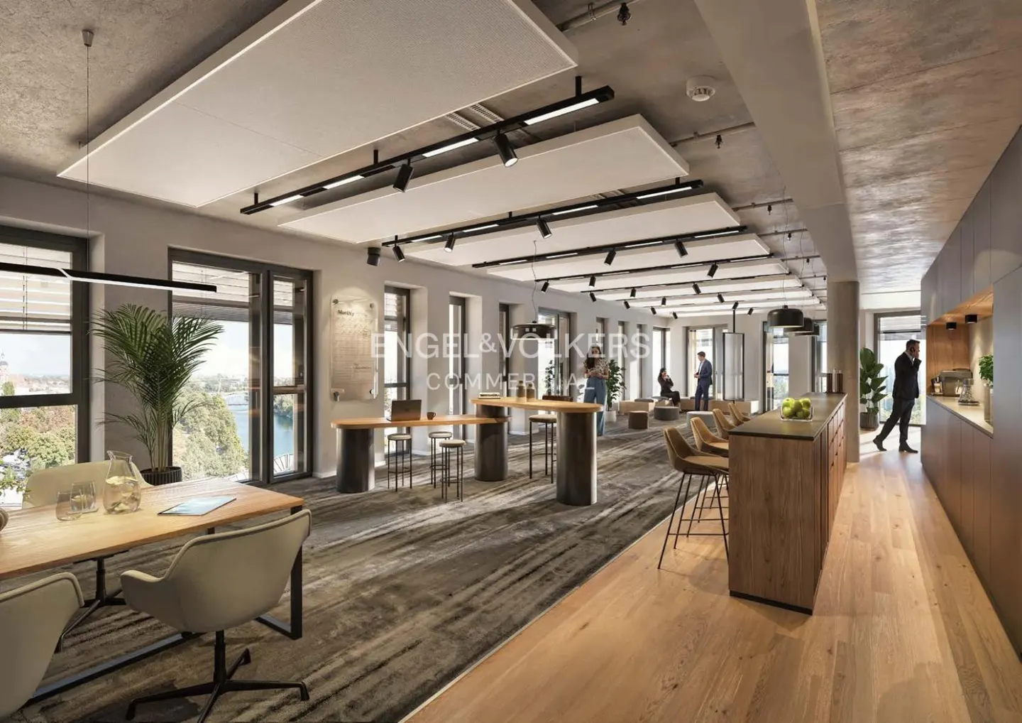 Open office space with tables, chairs, and bar stools. Large windows offer a view of the water. People are working and talking.