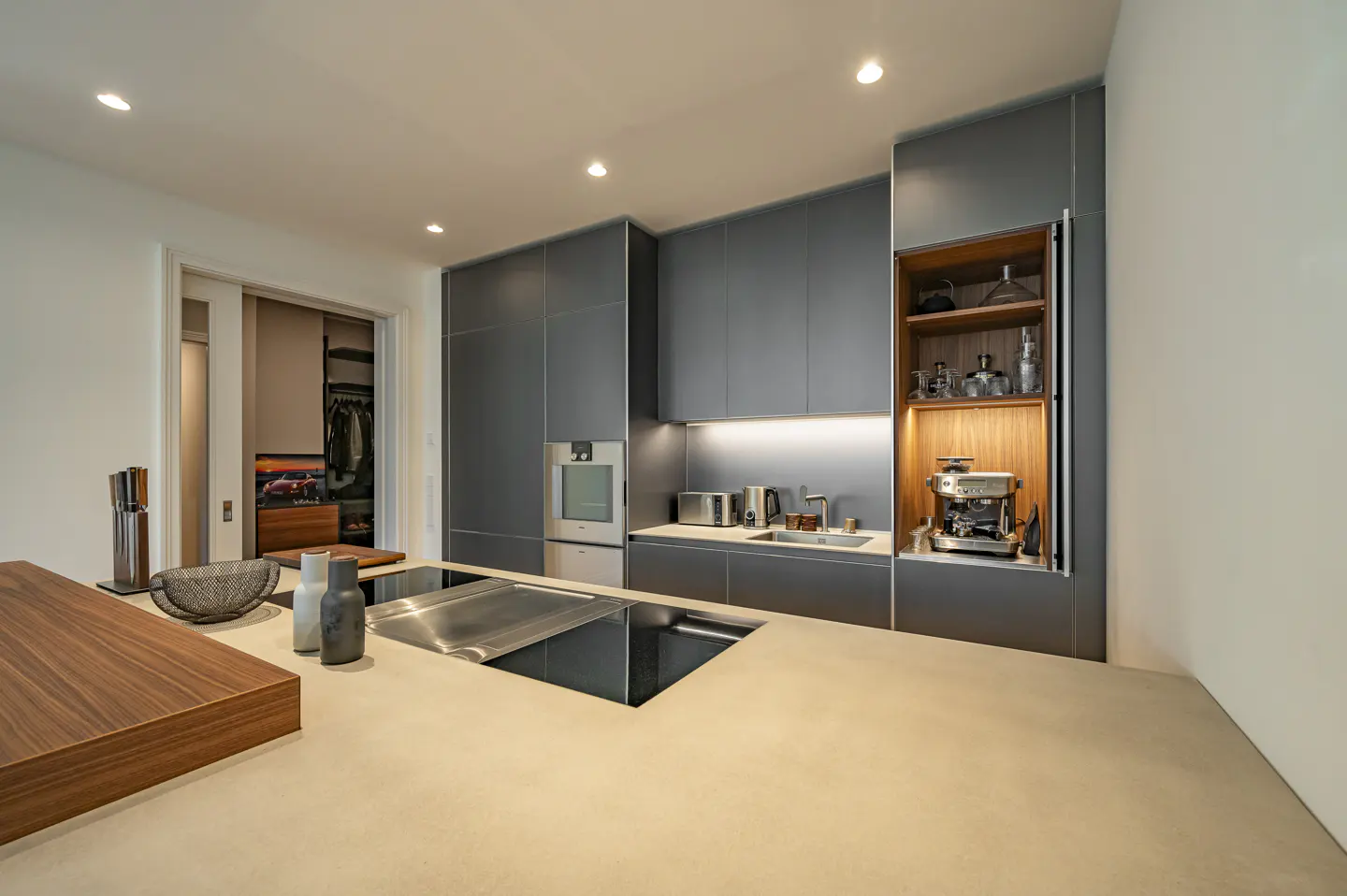 A modern kitchen with gray cabinets, stainless steel appliances, and a large island with a cooktop.