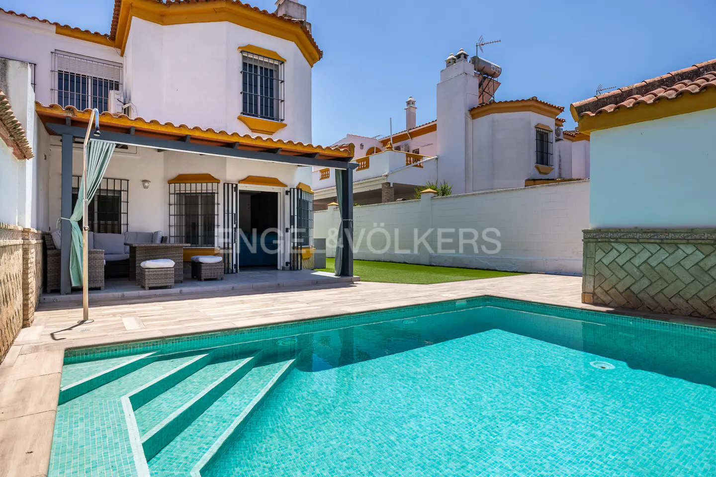 Exterior view of a white two-story house with a turquoise swimming pool in the foreground.