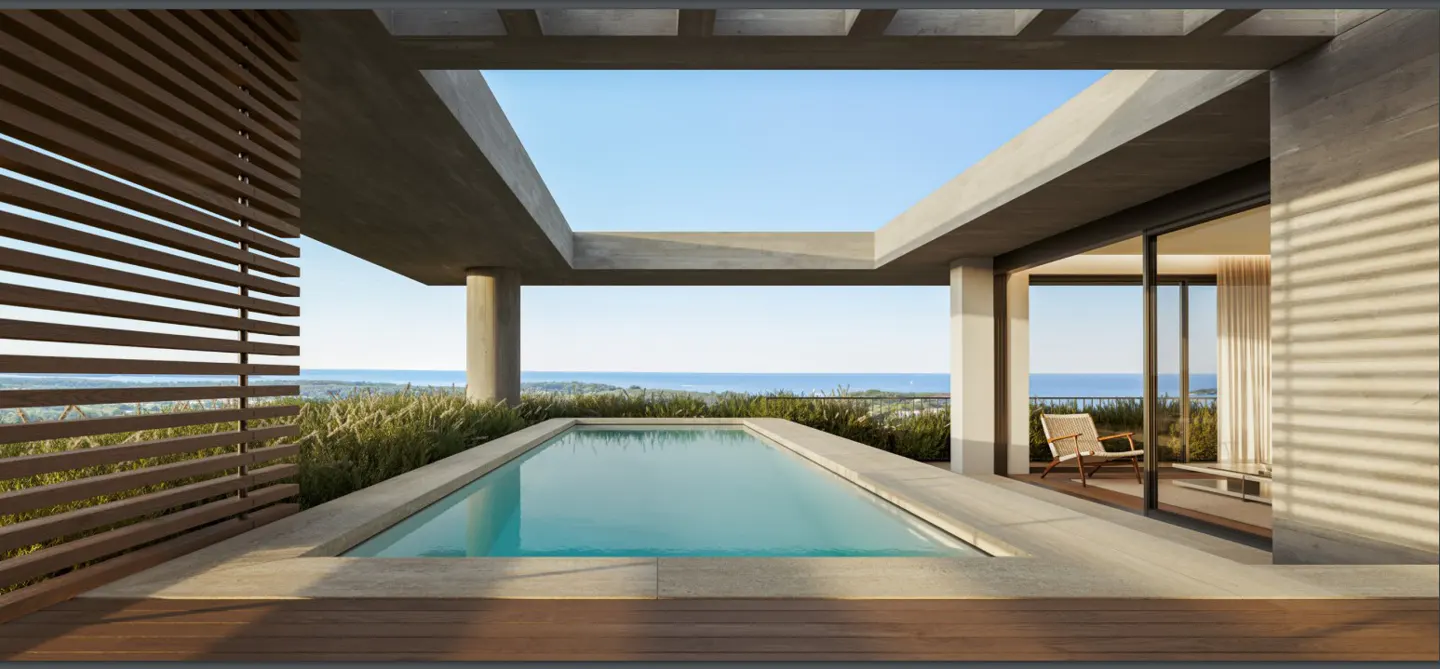 Outdoor pool with ocean view. Concrete pergola frames blue sky. Wooden deck and privacy screen. Chair visible through sliding glass doors.