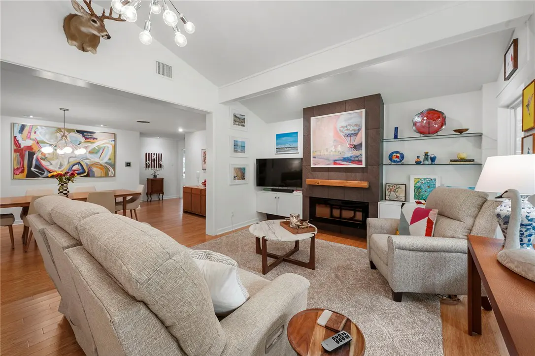 Living room with beige sofa, chair, and fireplace. A deer head mount hangs above the dining area with a colorful abstract painting.