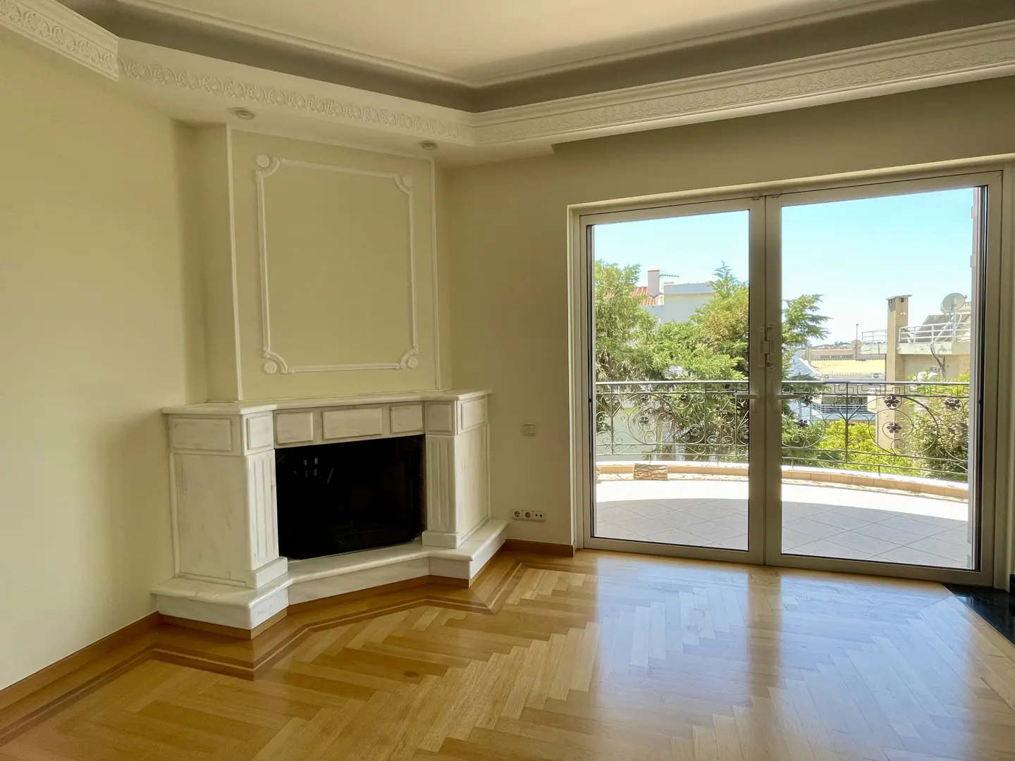 Bright living room with herringbone wood floors, a white fireplace, and sliding glass doors to a balcony with a view.