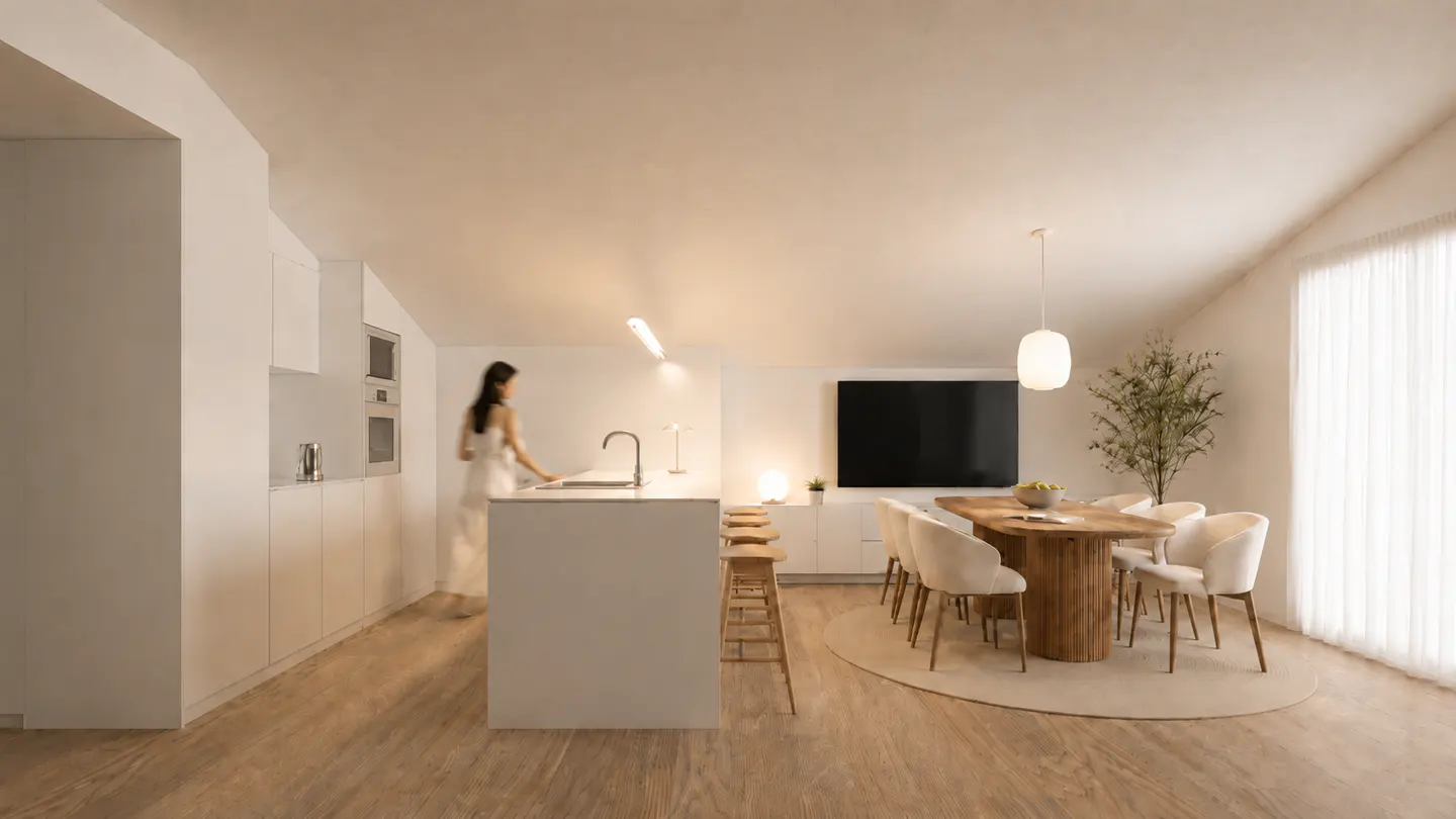 A woman in a white dress stands in a modern, minimalist kitchen with a wooden dining table and white chairs.