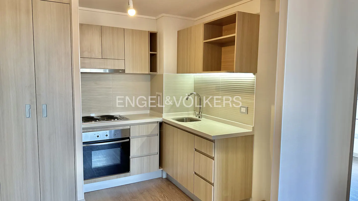 A bright kitchen with light wood cabinets, stainless steel appliances, and a sink with a chrome faucet.