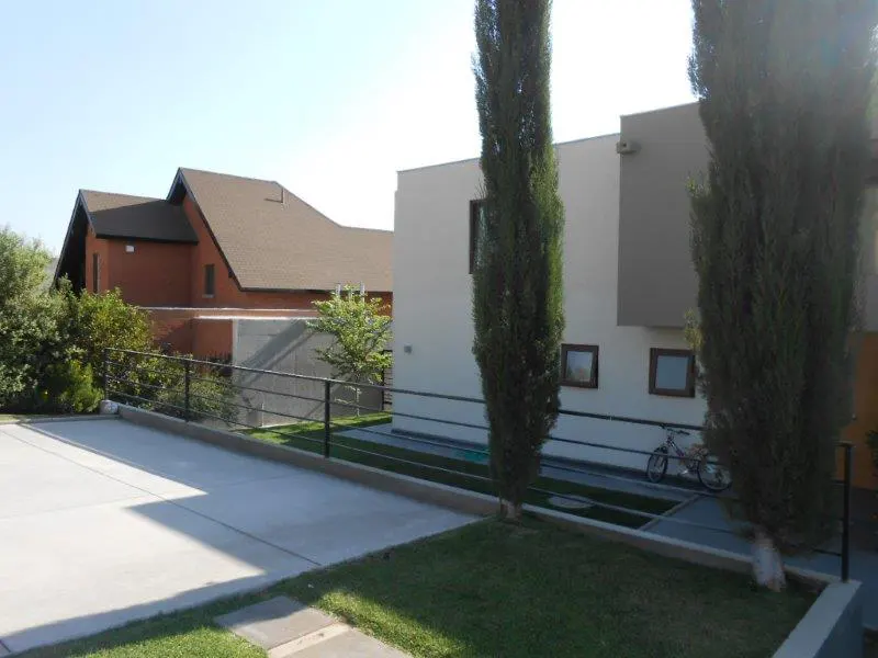 Exterior view of a modern two-story house with a driveway, lawn, and tall cypress trees. A bicycle is parked near the house.