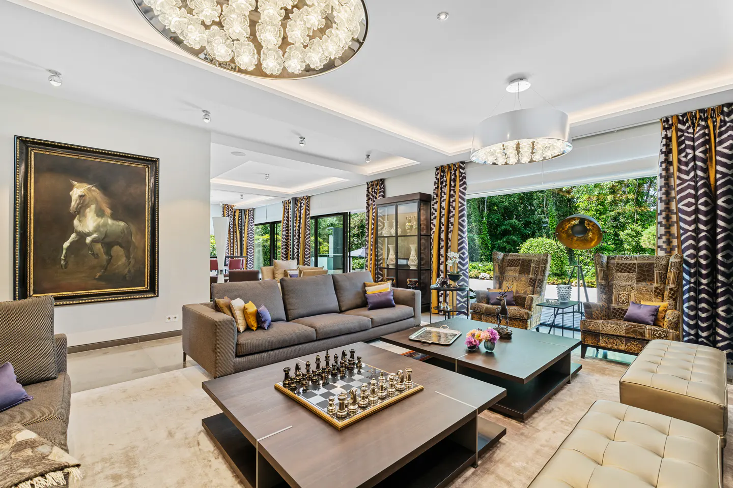 Luxurious living room with a grey sofa, chess set on a coffee table, patterned armchairs, and a large horse painting.