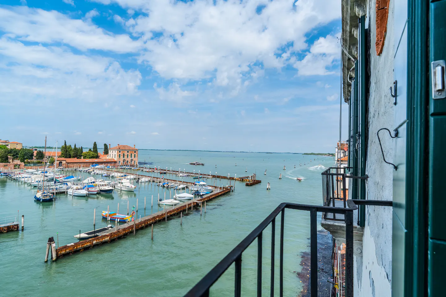 View from a balcony overlooking a marina filled with boats on a sunny day in Venice.