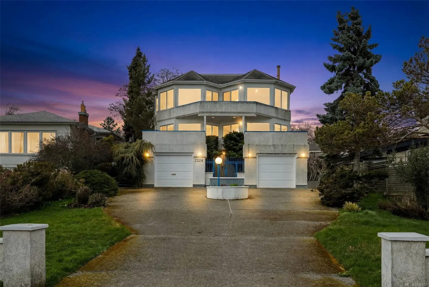Two-story white house with two garage doors and a circular second story under a blue and pink sky.