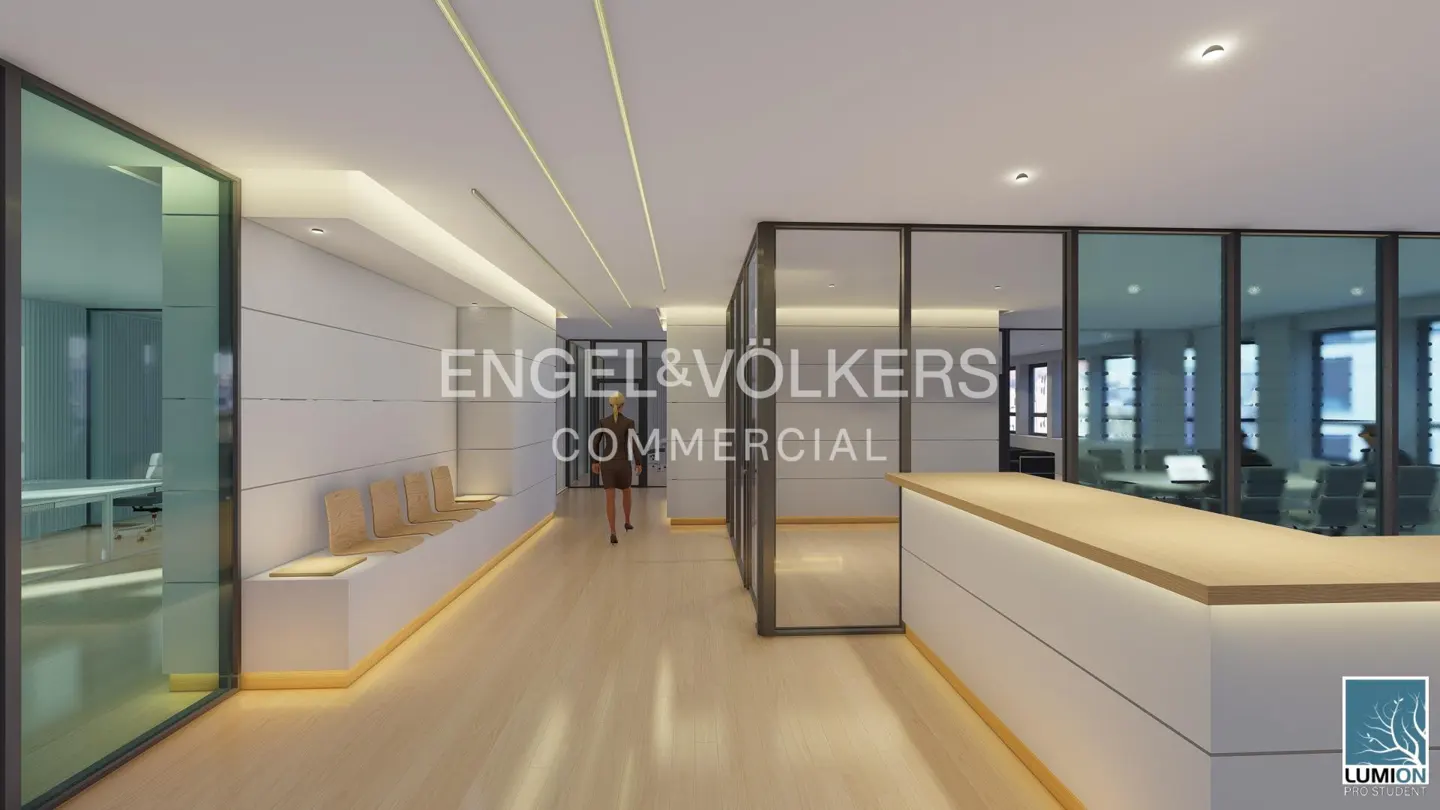 Modern office hallway with light wood floors, a white reception desk, glass-walled offices, and a person walking away.