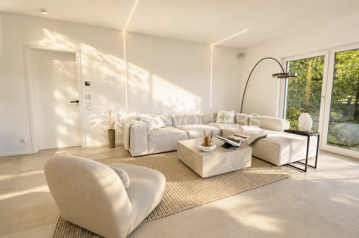 Modern living room with a beige sectional sofa, matching armchair, stone coffee table, and floor lamp on a jute rug.