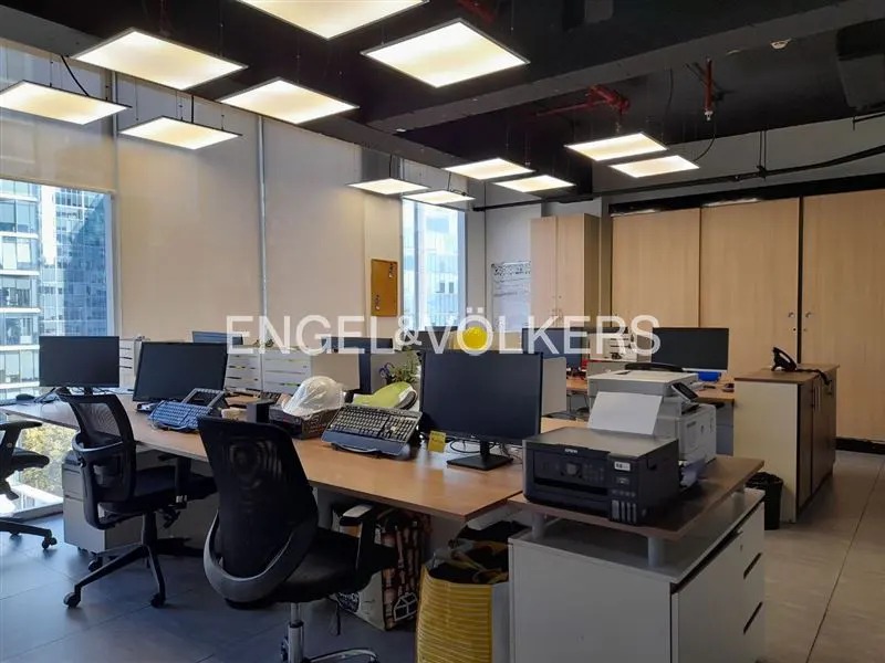 Bright office space with desks, computers, and chairs. Large windows offer city views. Engel & Völkers logo visible.