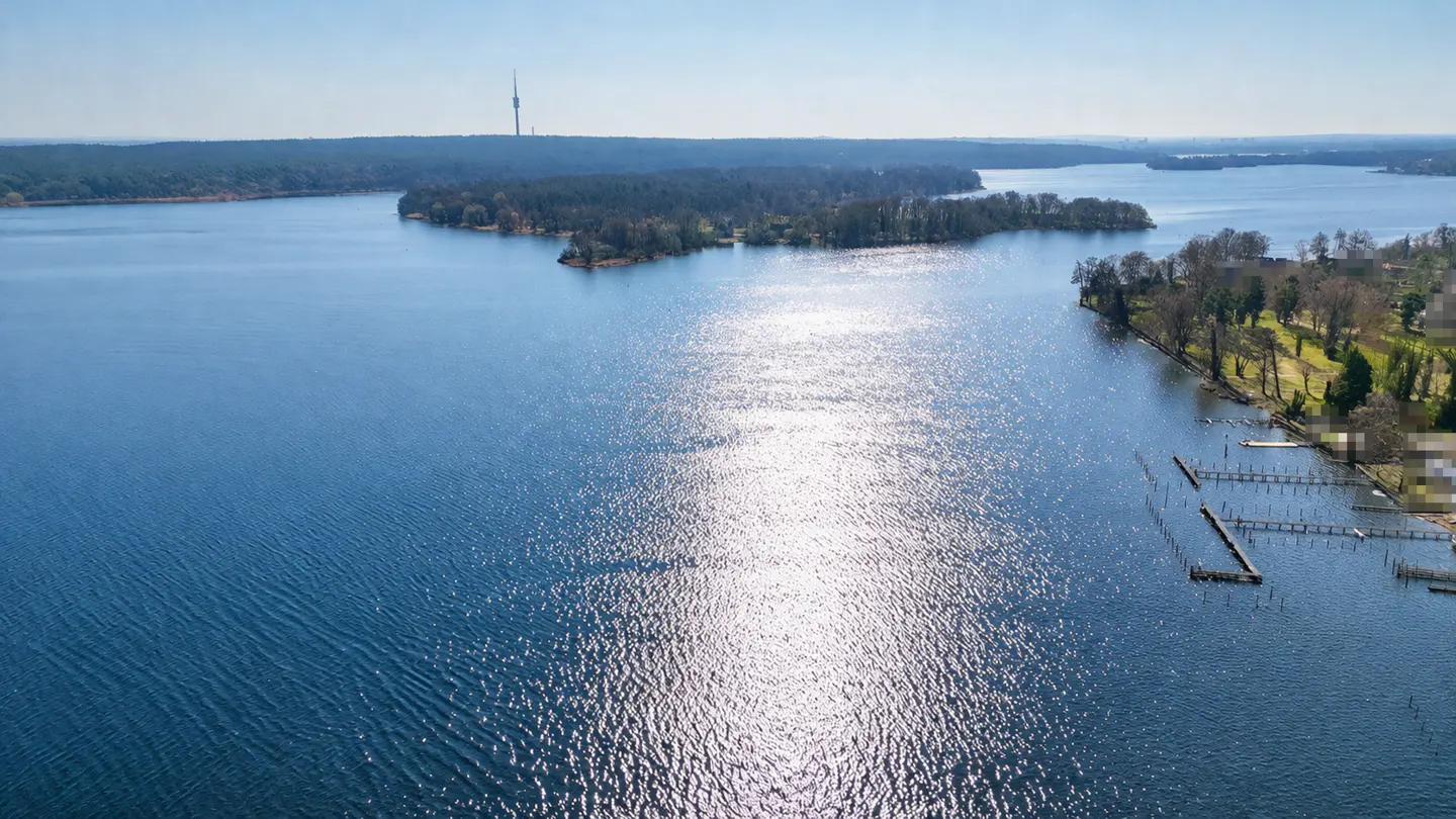 Aerial view of a blue lake with islands, trees, and docks on a sunny day.