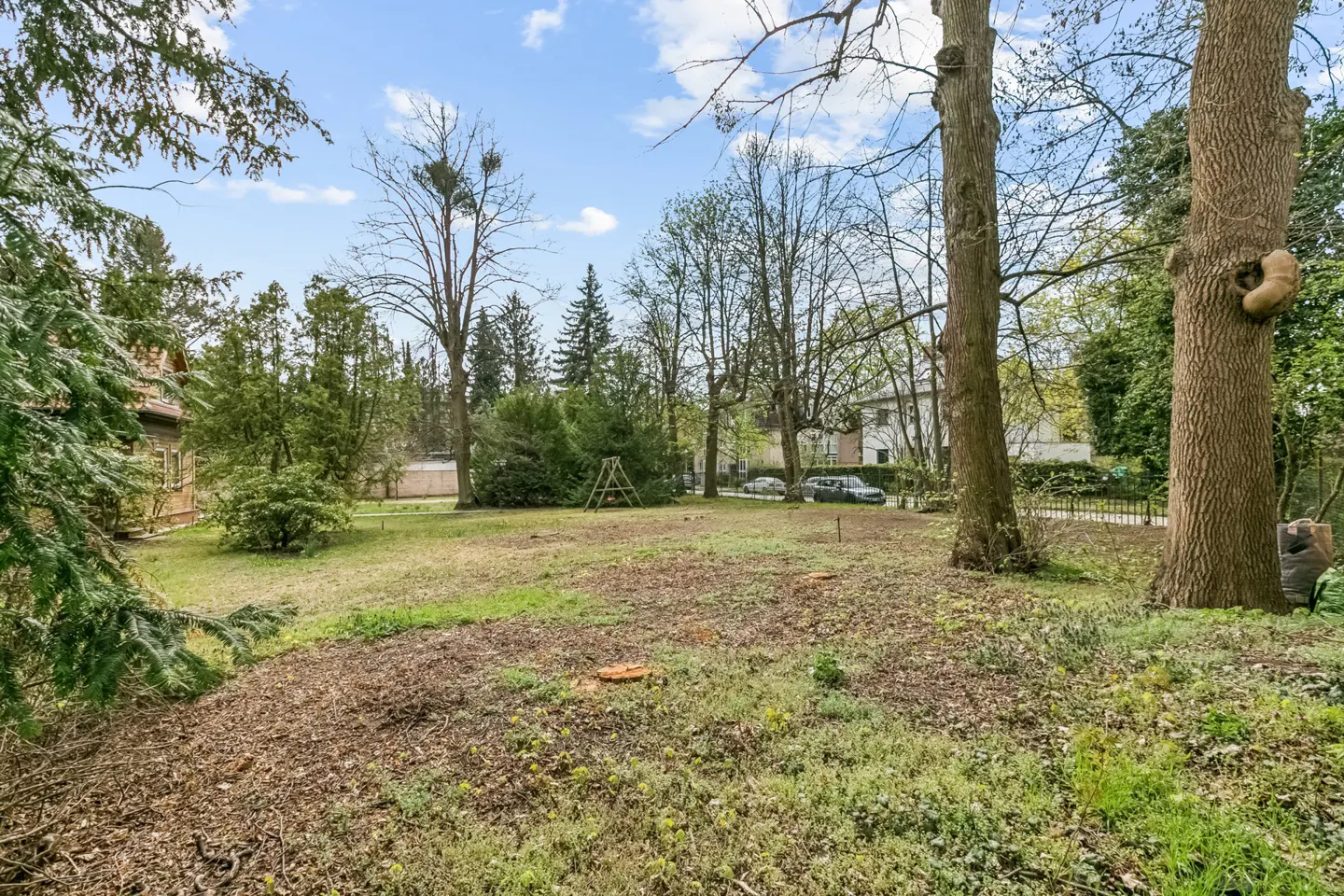 A large, grassy lot with trees and a blue sky with white clouds in the background.