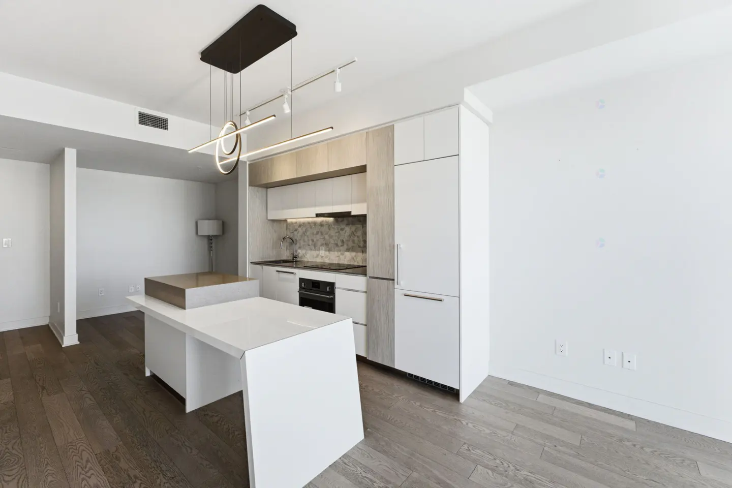 Bright, modern kitchen with white cabinets, island, and wood floors. A unique light fixture hangs above the island.