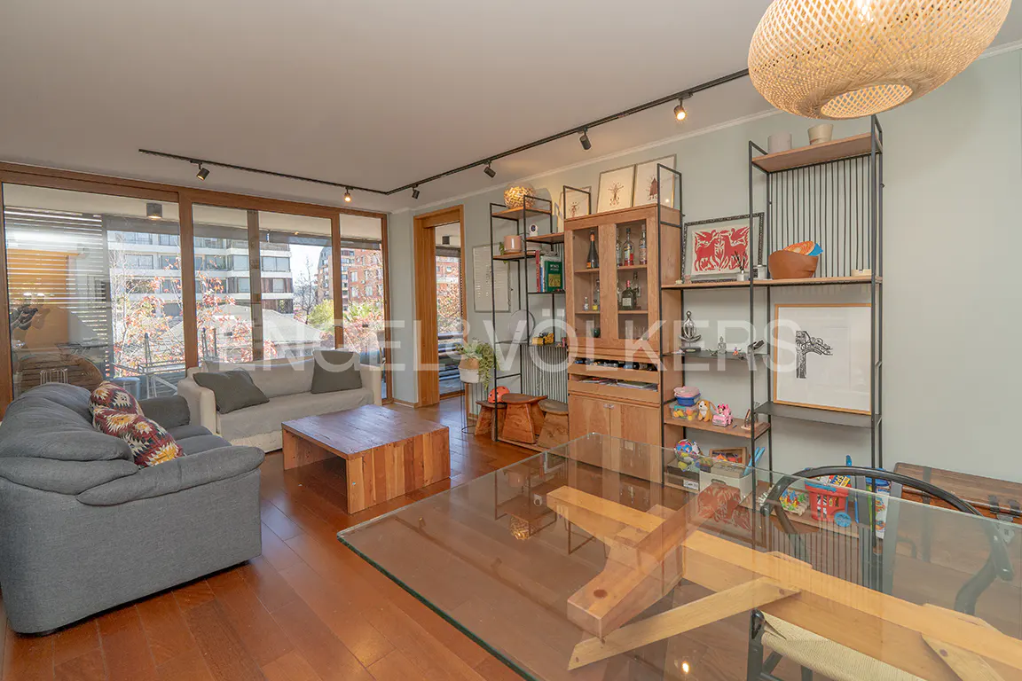 Living room with gray sofa, wood coffee table, and glass dining table. Shelves and a cabinet are against a light green wall.