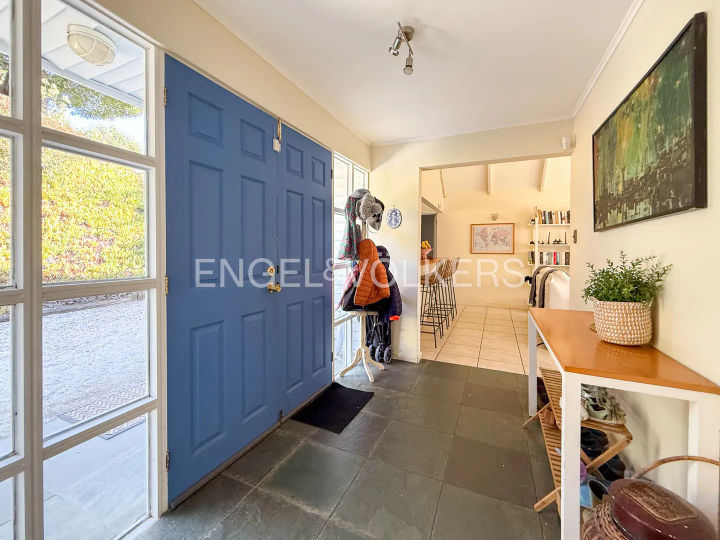A home's entryway with a blue door, coat rack, and a glimpse into the living room.