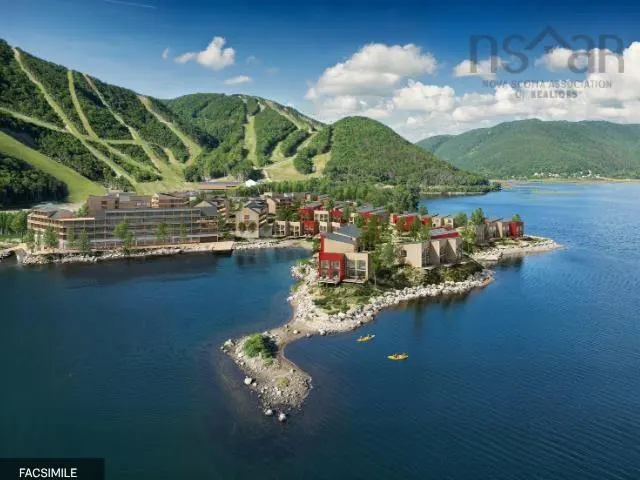 Aerial view of waterfront homes with red accents, nestled on a rocky peninsula in a blue lake, with mountains in the background. Two kayaks are visible in the water.