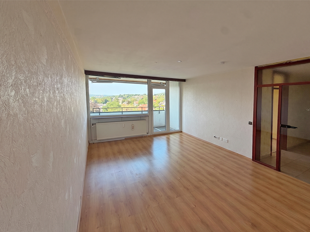 Empty living room with light wood floors, white walls, a large window with a balcony, and a glass-paneled door. [AI-generated text]